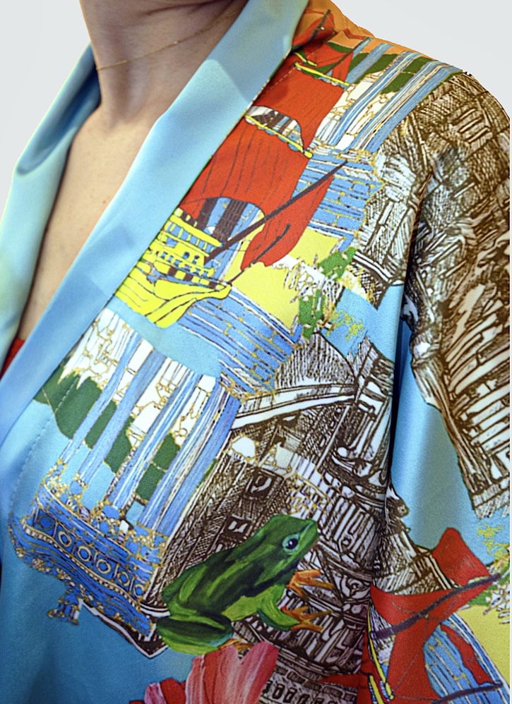 Detail of a printed garment featuring a green frog, red sails and hand drawn architecture