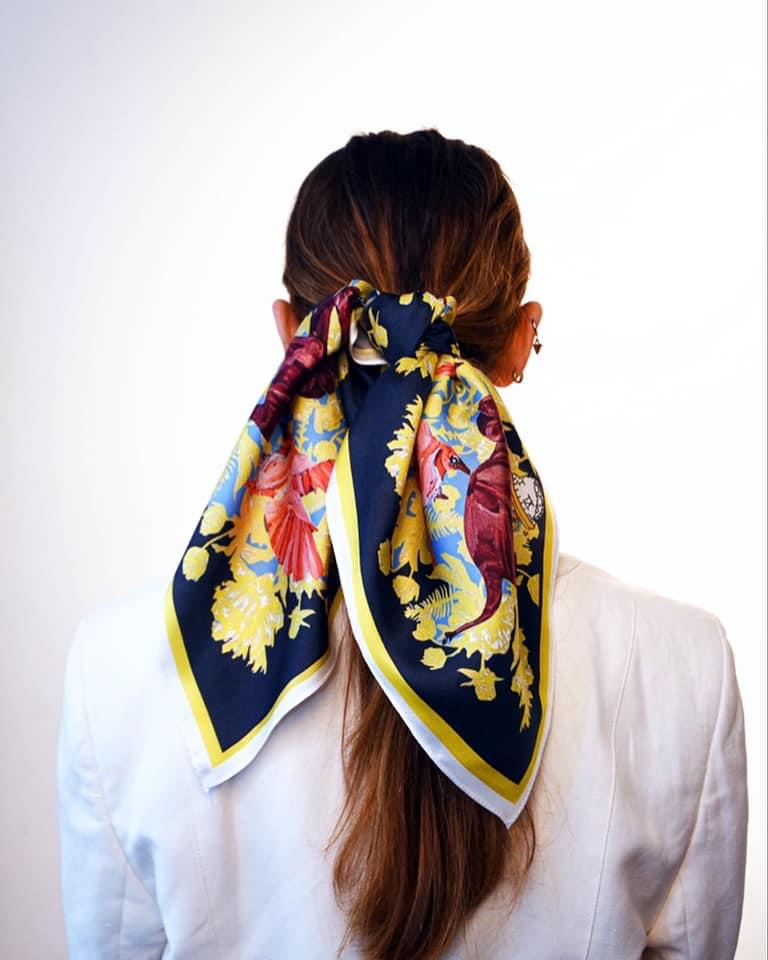 Back view of a model in a white blazer wearing a navy and yellow silk scarf